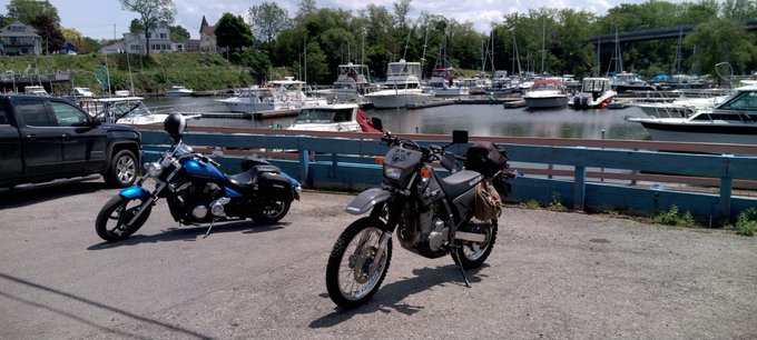 Motorcycles parked and resting in the boat harbor.