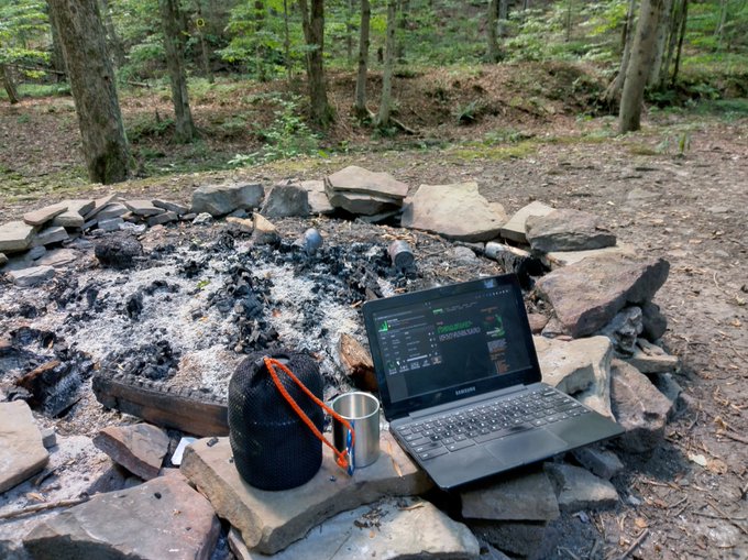 Laptop and cooking kit by a fire pit.